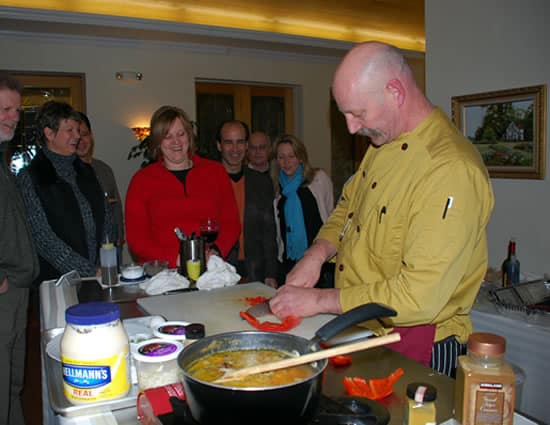 People surrounding a kitchen station with a chef preparing a meal