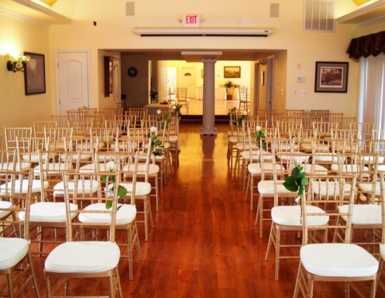 Large room with hardwood flooring set up for a wedding ceremony