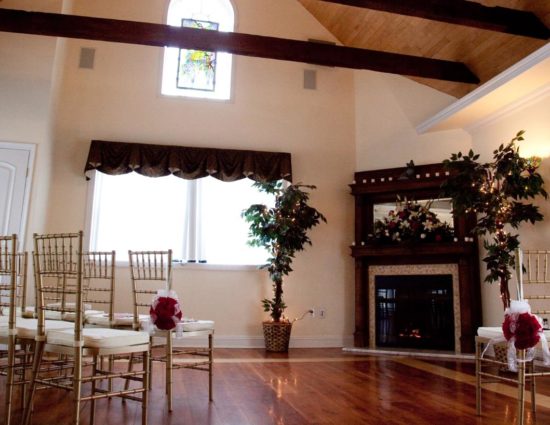 Large room with hardwood flooring and fireplace in the corner set up for a wedding ceremony