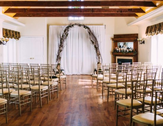 Large room with hardwood flooring set up for a wedding ceremony with large alter at the front