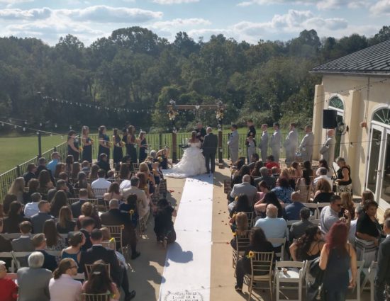 Patio set up for wedding ceremony with father giving away the bride in a white dress