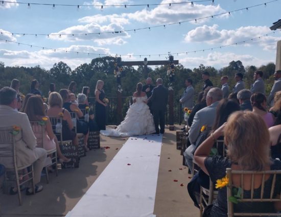 Patio set up for wedding ceremony with father giving away the bride in a white dress