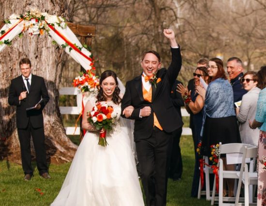 Bride with white dress and groom with black suit walking down the aisle together