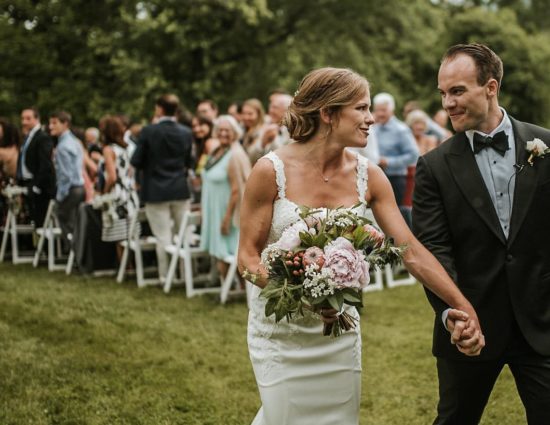 Bride with white dress and groom with black suit walking down the aisle together