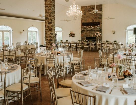 Large room set up for a wedding reception with cream tablecloths and gray napkins