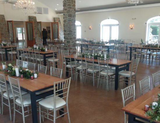 Large room set up for a wedding reception with flower garlands on all tables