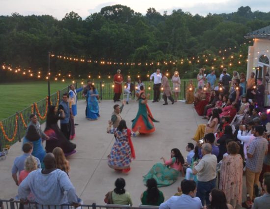 Large wedding party on concrete patio with people watching a group dancing