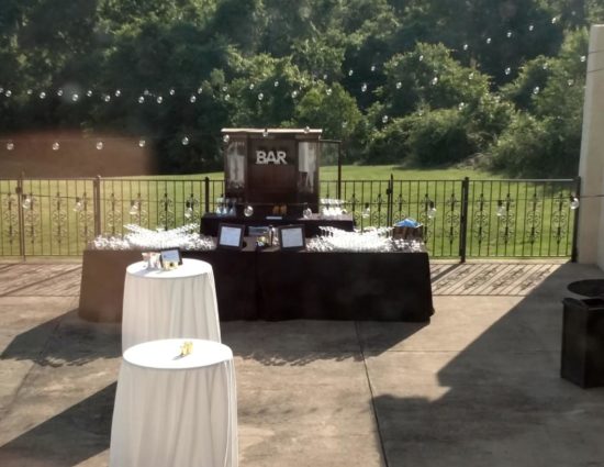 Large concrete patio set up for wedding reception, including a bar station