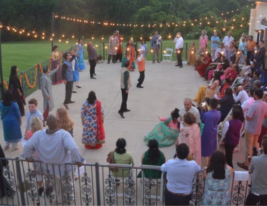 Large wedding party on concrete patio with people watching a group dancing