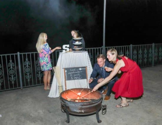 People roasting a marshmallow in a fire pit next to a smore station