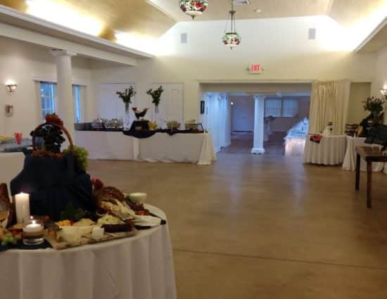 Large room set up for a wedding buffet with a cheese and crackers station, drink station, and buffet station