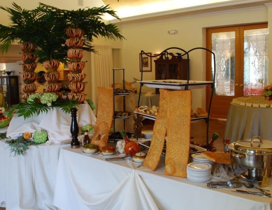 Large room with concrete flooring and large tables with white tablecloths and lots of food