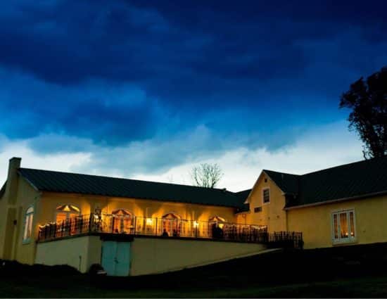 Back view of events building with patio lighted up and the sky dark as the sun sets