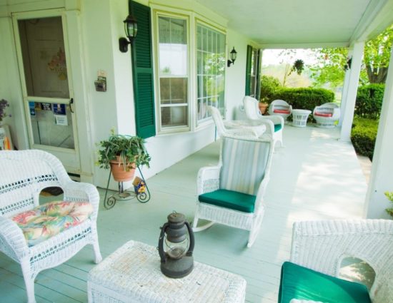 Porch with white wicker patio furniture with green cushions