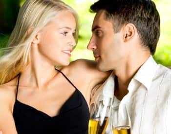 Woman with black shirt and man with white shirt looking at each other holding glasses with champagne