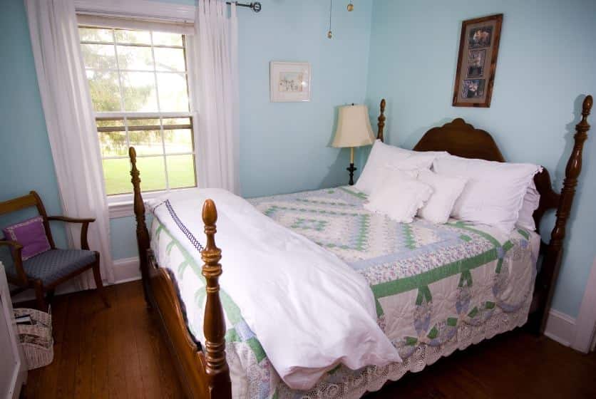 Bedroom with dark wood furntiure, green, light blue and white quilt, and light blue walls