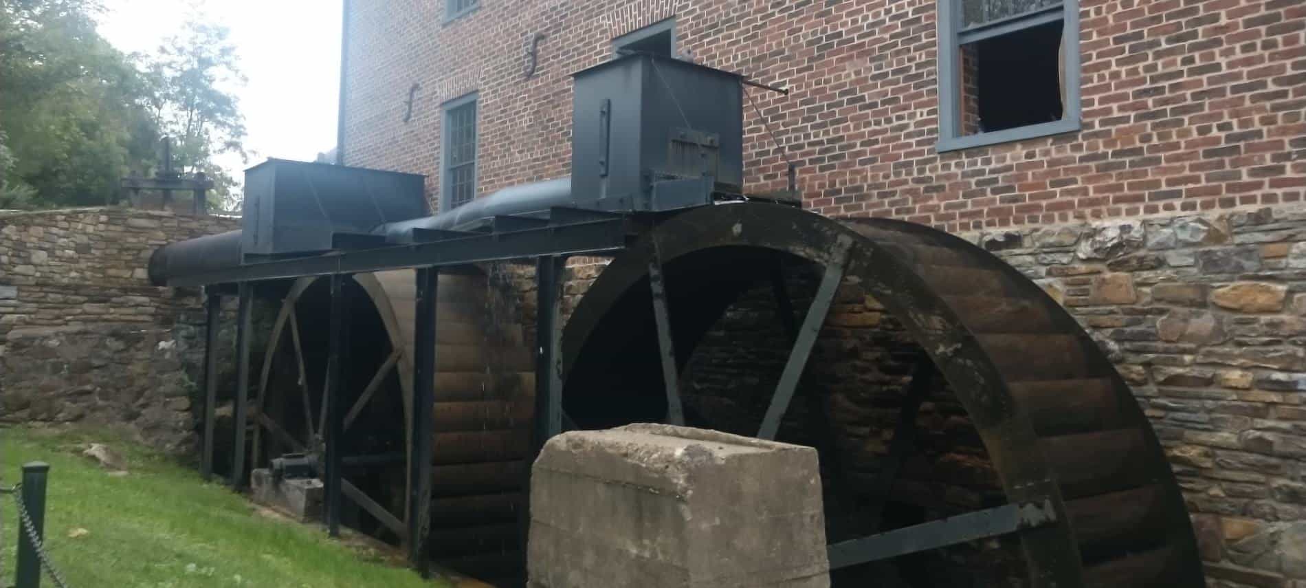 Two large wheels being moved by water generating electricity for old brick building
