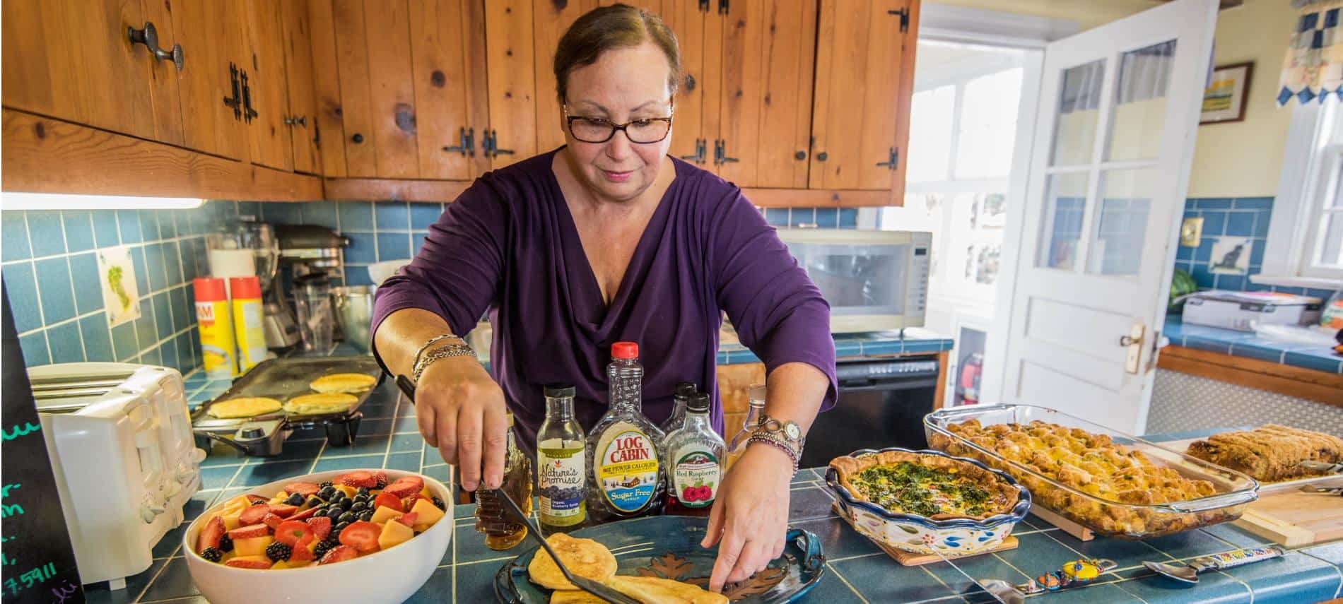 Person in kitchen making multiple dishes for breakfast