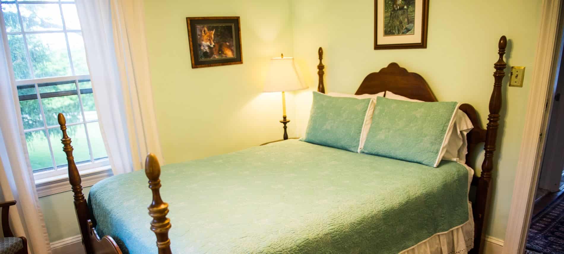 Bedroom with dark wood furntiure, green quilt, and light blue walls