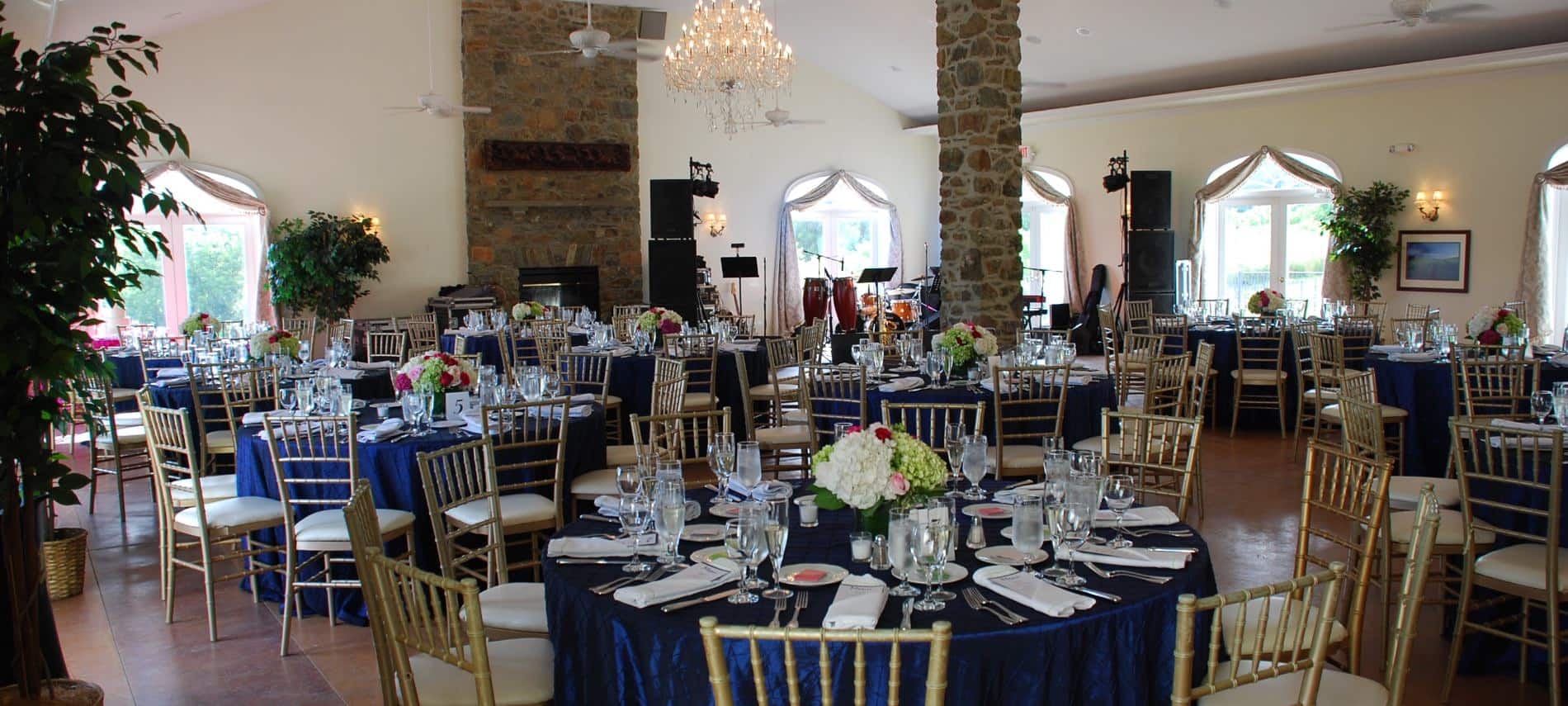 Large room decorated for a wedding reception with blue tablecloths and white napkins