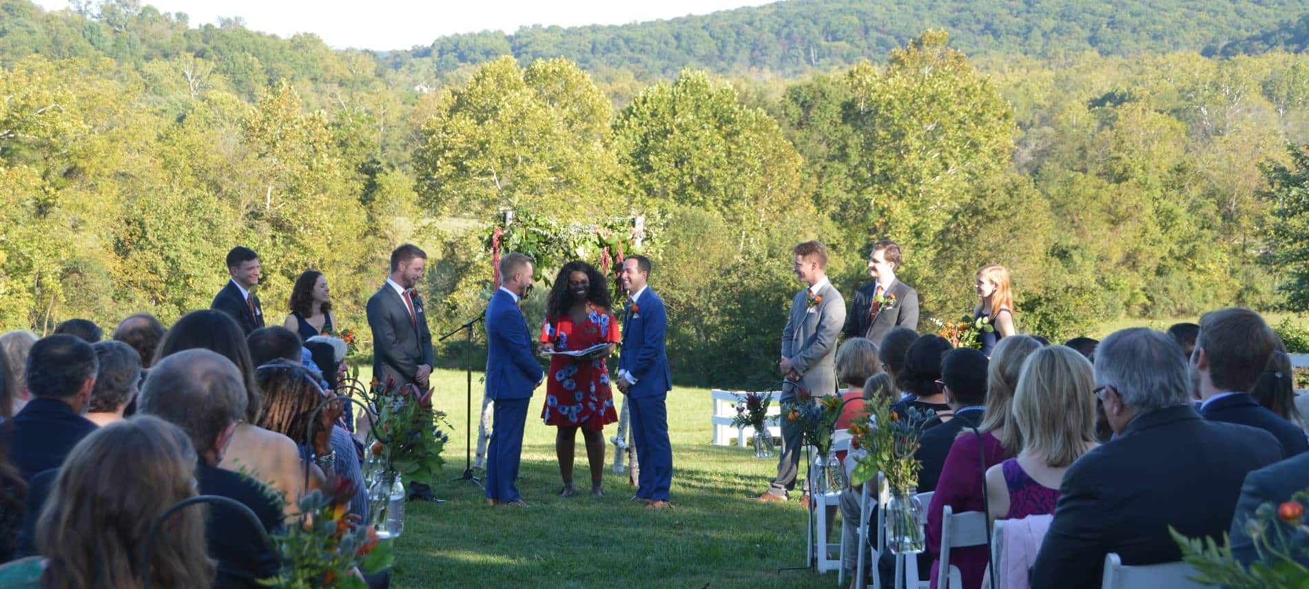 Wedding taking place with many large trees and rolling hills in the background