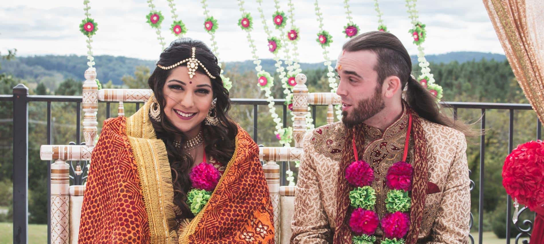Bride and groom in traditional Indian wedding attire sitting next to each other