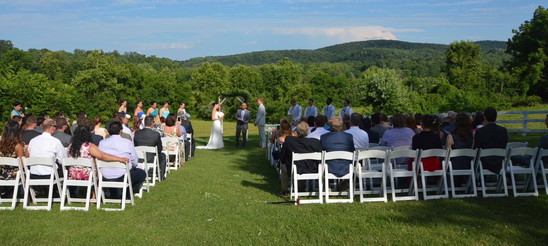 Wedding taking place with a very many trees and rolling hills in the background
