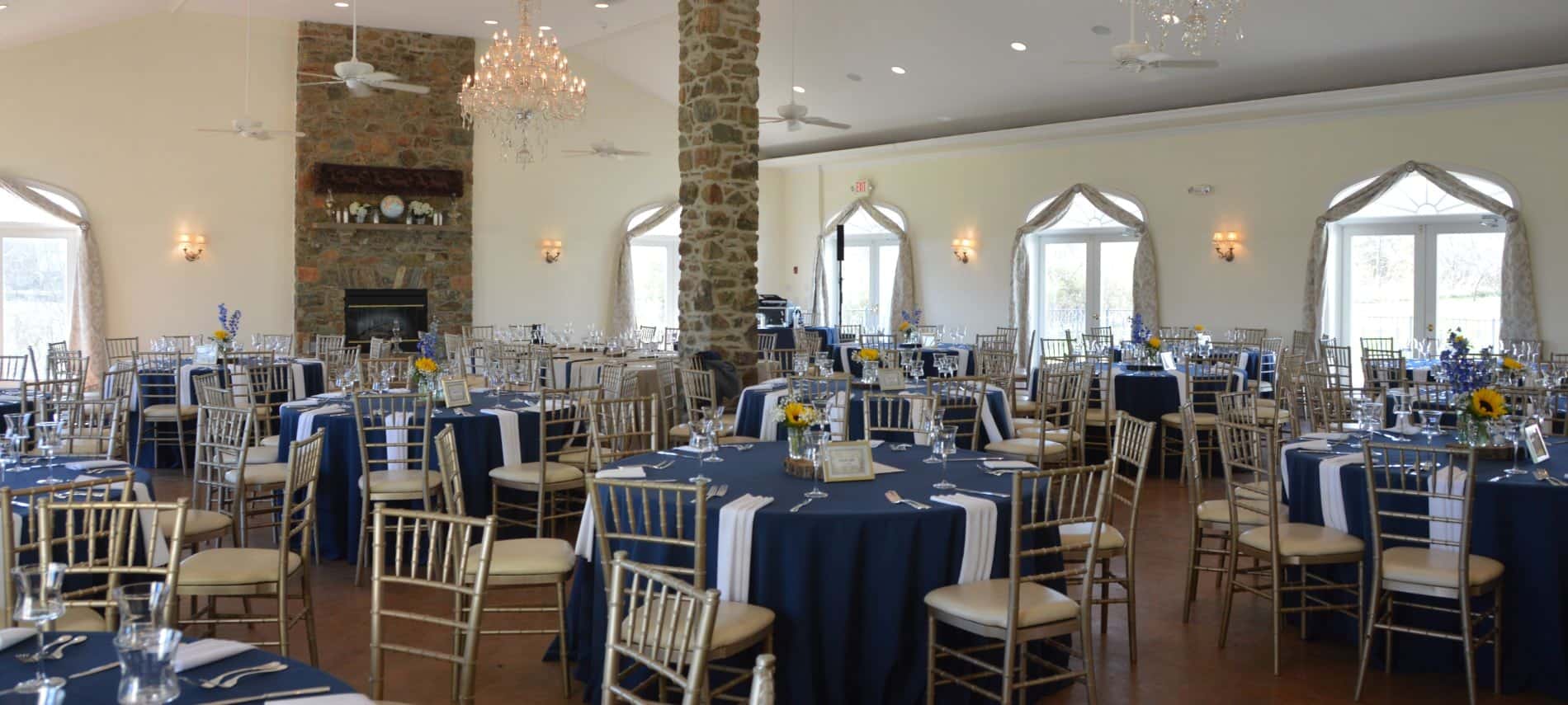 Large room decorated for a wedding reception with navy tablecloths and white napkins