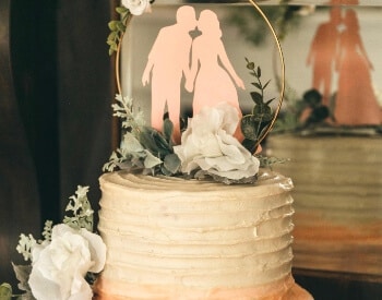 The top tier of a wedding cake with a wedding couple figurine on top.