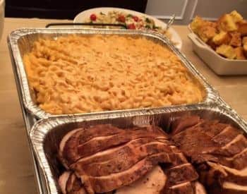 Aluminum serving dishes with mac and cheese and barbecued meat