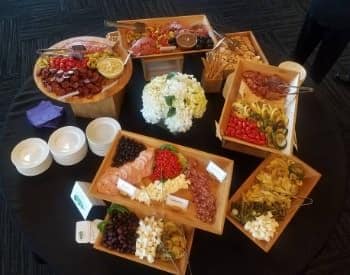 Multiple wood trays with a variety of meats, cheeses, vegetables, olives, and sauces