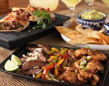 Multiple Mexican dishes on black and white serving trays