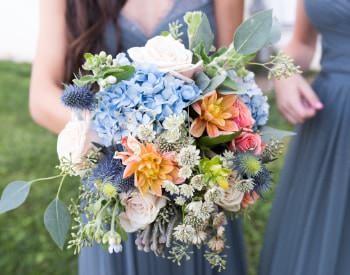 Close up view of bridal bouquet filled with a variety of blue, pink, orange, purple, and green flowers